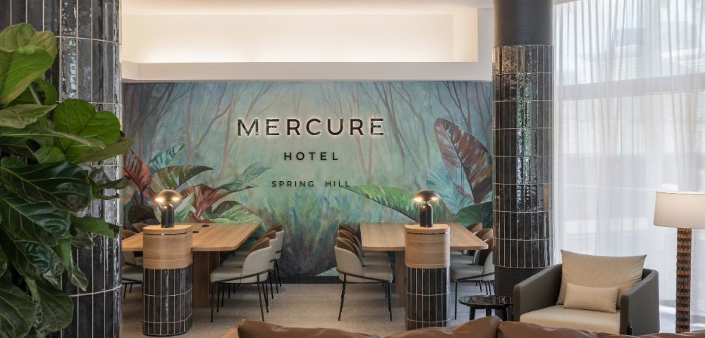 Interior lobby of Mercure Hotel Spring Hill with a lush green jungle mural and modern seating area.