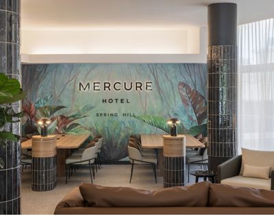 Interior lobby of Mercure Hotel Spring Hill with a lush green jungle mural and modern seating area.