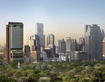 City skyline with modern skyscrapers behind a large green park under a clear sky at sunset.
