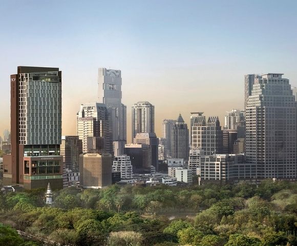 City skyline with modern skyscrapers behind a large green park under a clear sky at sunset.