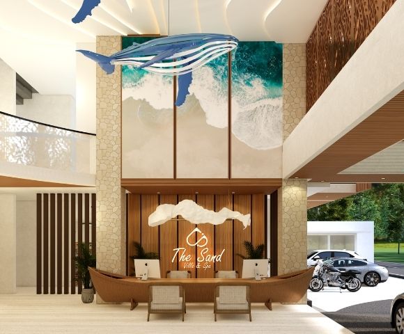 Spacious resort reception area with a decorative central desk, high ceilings, natural light, and landscaped outdoor views