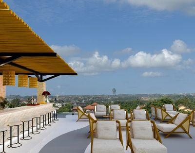 Open-air rooftop bar with lounge seating, bar stools, and panoramic views under a clear blue sky