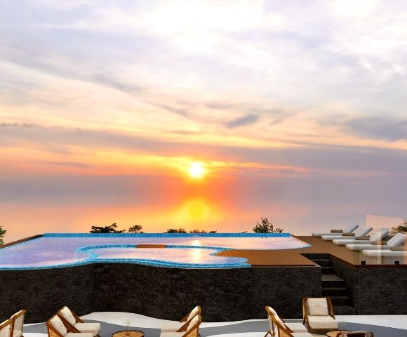 Infinity pool overlooking the ocean at sunset, with lounge seating and colorful evening skies.