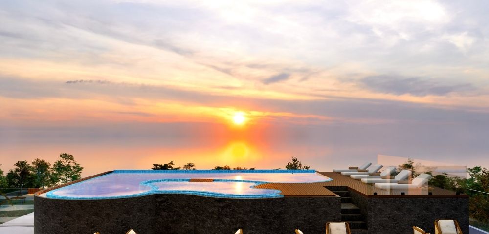 Infinity pool overlooking the ocean at sunset, with lounge seating and colorful evening skies.