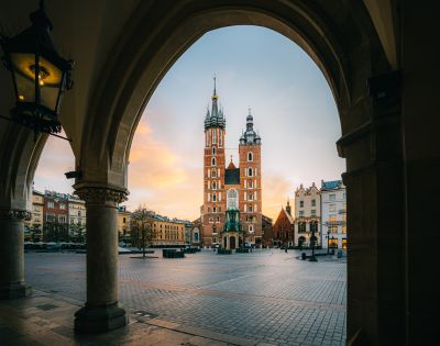 View through arched colonnade of St. Mary's Basilica in Krakow's Main Market Square at dawn.