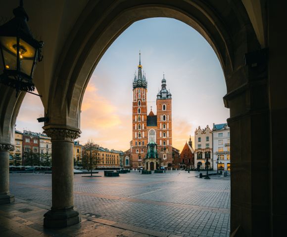 View through arched colonnade of St. Mary's Basilica in Krakow's Main Market Square at dawn.