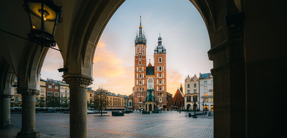 View through arched colonnade of St. Mary's Basilica in Krakow's Main Market Square at dawn.