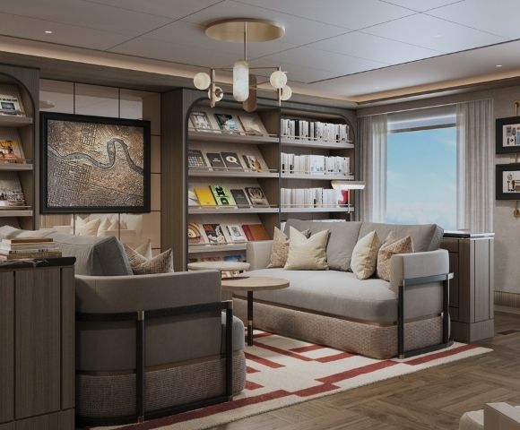 A cozy library lounge with bookshelves filled with books and magazines, comfortable sofas, armchairs, a small coffee table, and a framed map on the wall, bathed in soft light.