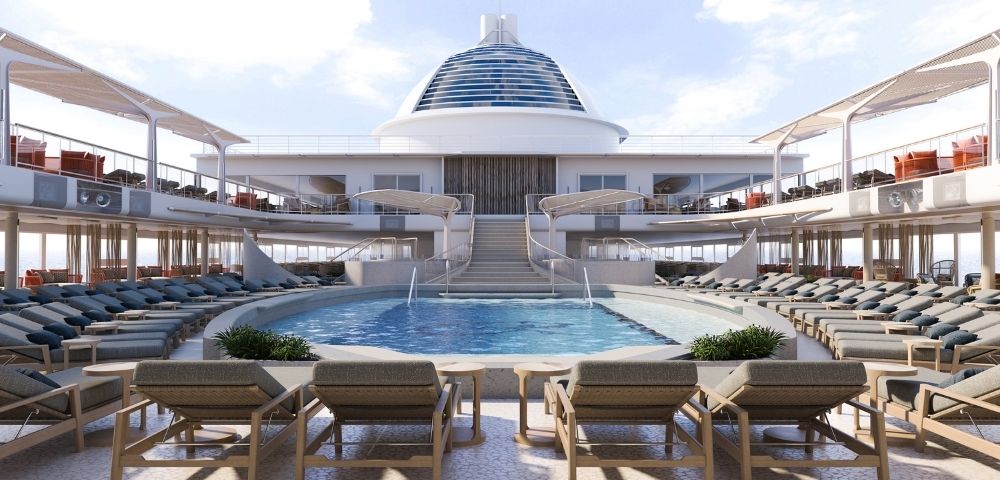 An empty deck area of a cruise ship with a swimming pool, rows of lounge chairs, and a bar area.
