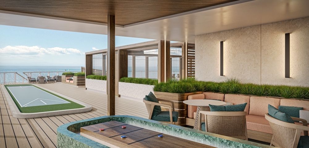 A modern outdoor lounge area with a shuffleboard court, a full-size shuffleboard court, seating, and tables overlooking the ocean.