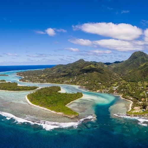 Aerial view of lush, green islands surrounded by turquoise waters and a clear blue sky.