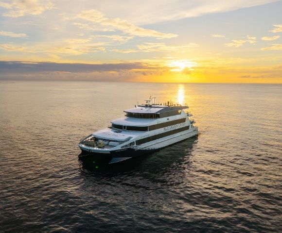 A luxury yacht navigating calm waters during sunset.
