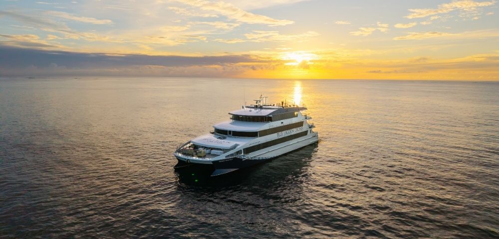 A luxury yacht navigating calm waters during sunset.
