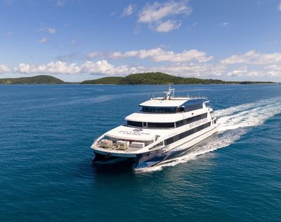A luxury catamaran cruising on turquoise waters with a tropical island in the background.