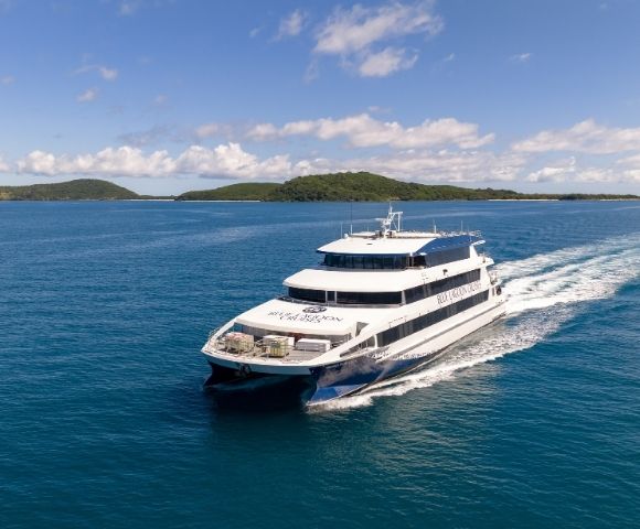A luxury catamaran cruising on turquoise waters with a tropical island in the background.