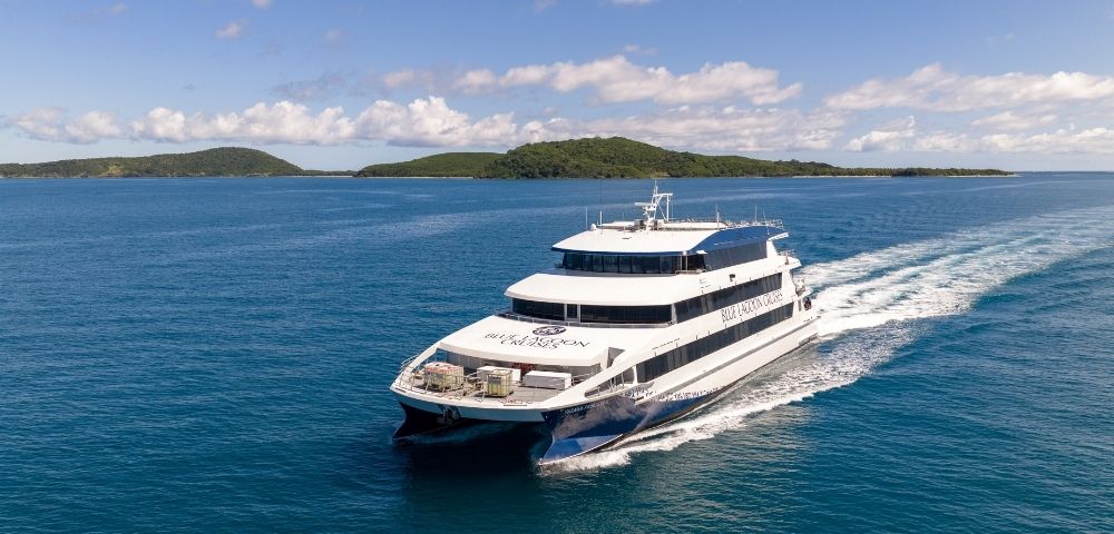 A luxury catamaran cruising on turquoise waters with a tropical island in the background.