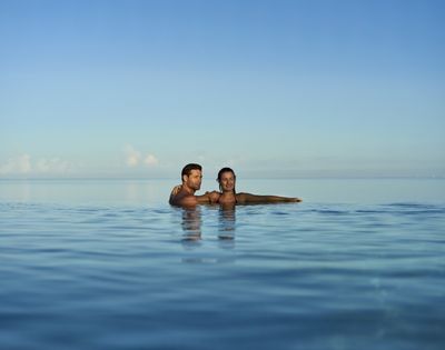 A couple enjoying a peaceful moment in a calm body of water, with clear blue skies above.