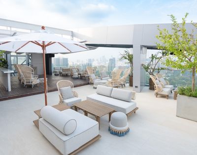 A rooftop lounge area featuring comfortable seating, umbrellas, and a view of the city skyline.