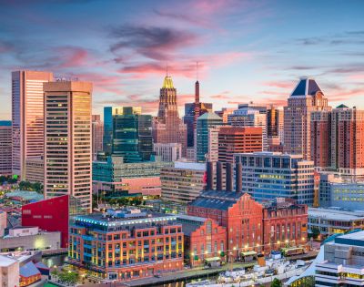 A panoramic view of Baltimore, MD, showcasing its skyline, harbor, and notable landmarks under a clear blue sky.