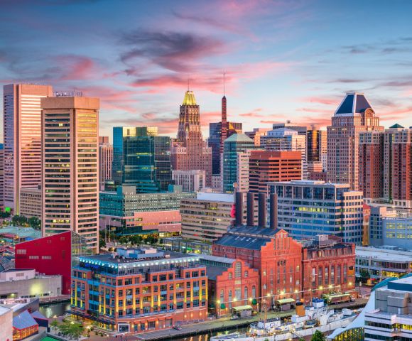 A panoramic view of Baltimore, MD, showcasing its skyline, harbor, and notable landmarks under a clear blue sky.