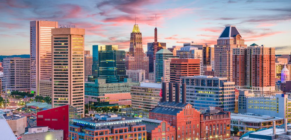 A panoramic view of Baltimore, MD, showcasing its skyline, harbor, and notable landmarks under a clear blue sky.