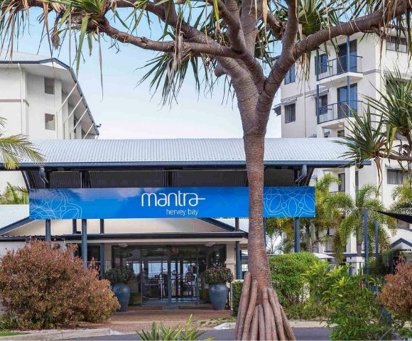 Entrance of the Mantra Hotel, surrounded by palm trees and greenery.