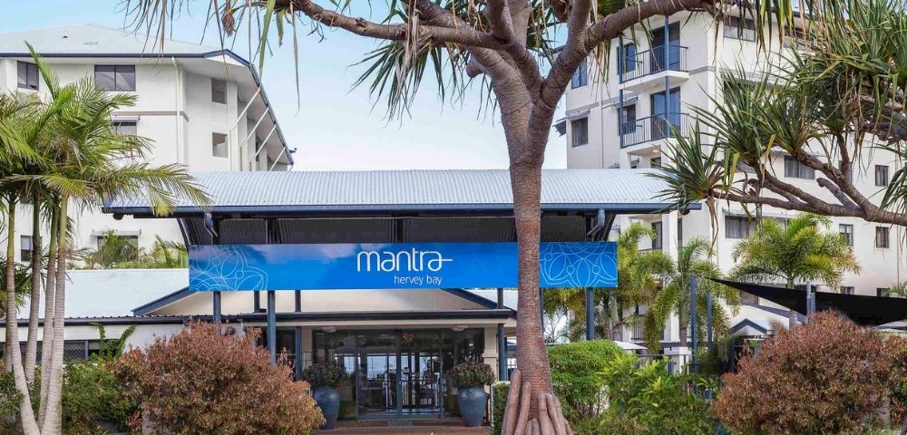 Entrance of the Mantra Hotel, surrounded by palm trees and greenery.