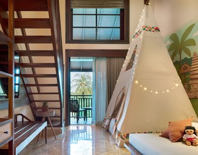 A cozy room featuring a staircase, a tent structure, and tropical-themed decor with dolls on a bed.