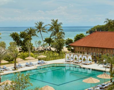 A thatched gazebo surrounded by lush greenery and a tranquil pool area.