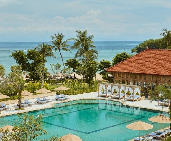 A thatched gazebo surrounded by lush greenery and a tranquil pool area.