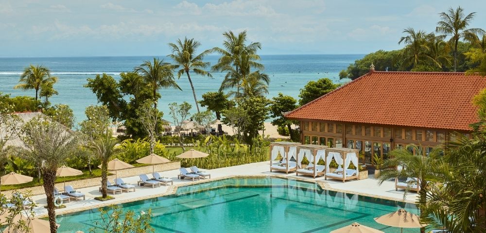 A thatched gazebo surrounded by lush greenery and a tranquil pool area.