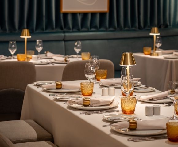 Private dining setup with table settings and decorative artwork in the Amphora restaurant.