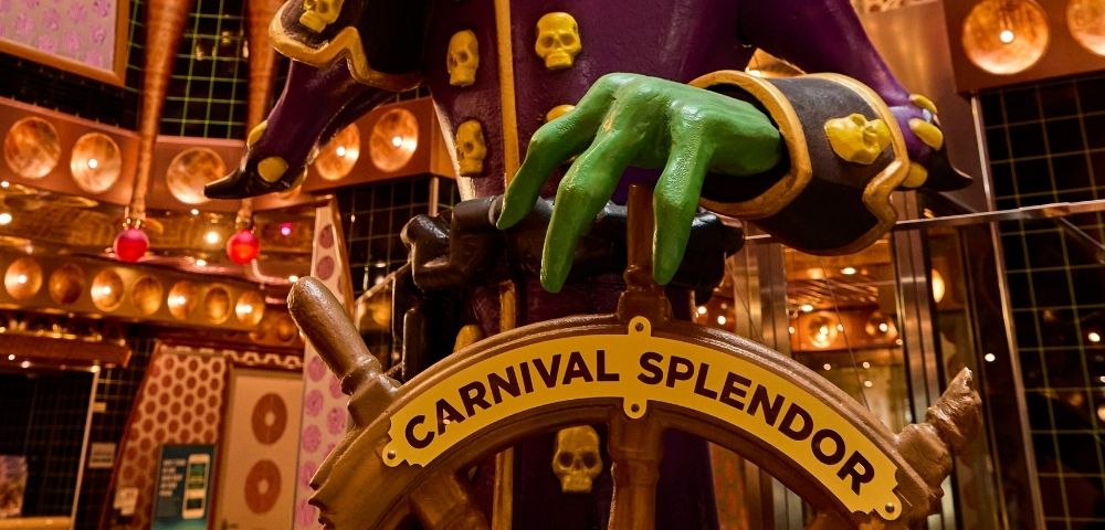 Colorful atrium centerpiece sculpture surrounded by multiple decks and decorative lighting aboard a cruise ship.v