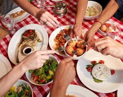 Italian dining spread with shared dishes and checkered tablecloth in a casual restaurant setting.