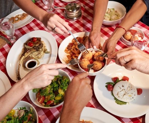 Italian dining spread with shared dishes and checkered tablecloth in a casual restaurant setting.