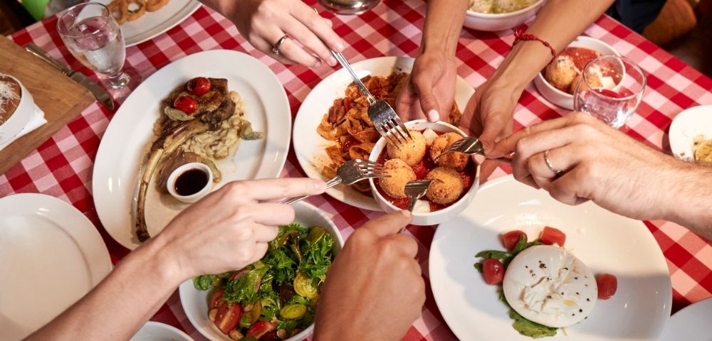Italian dining spread with shared dishes and checkered tablecloth in a casual restaurant setting.