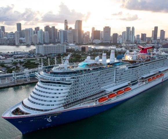 Carnival Celebration cruise ship sailing near a city skyline and waterfront.