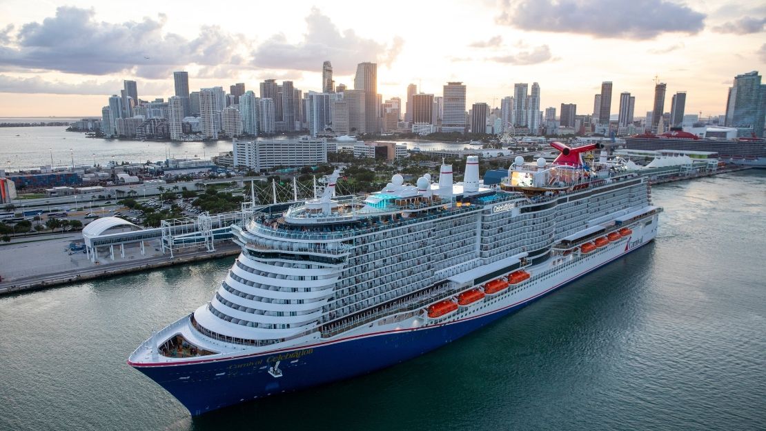 Carnival Celebration cruise ship sailing near a city skyline and waterfront.