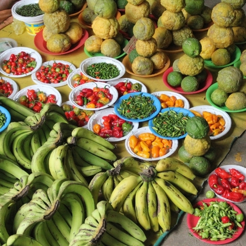 Colorful market stall overflowing with bananas, citrus, peppers and tomatoes, creating a vibrant, abundant scene.