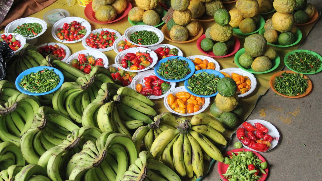 Colorful market stall overflowing with bananas, citrus, peppers and tomatoes, creating a vibrant, abundant scene.