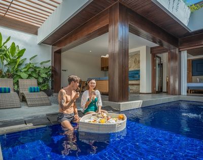 A couple enjoys a floating breakfast in a private pool villa.