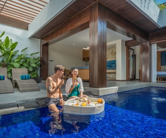 A couple enjoys a floating breakfast in a private pool villa.