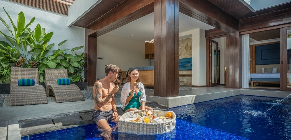 A couple enjoys a floating breakfast in a private pool villa.