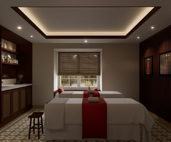 A serene spa treatment room with two massage tables, each adorned with red runners and white towels, bathed in soft, indirect ceiling lighting.