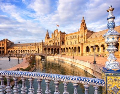 A view of a historic building with ornate architecture beside a canal, under a partly cloudy sky.