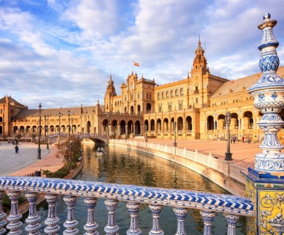 A view of a historic building with ornate architecture beside a canal, under a partly cloudy sky.