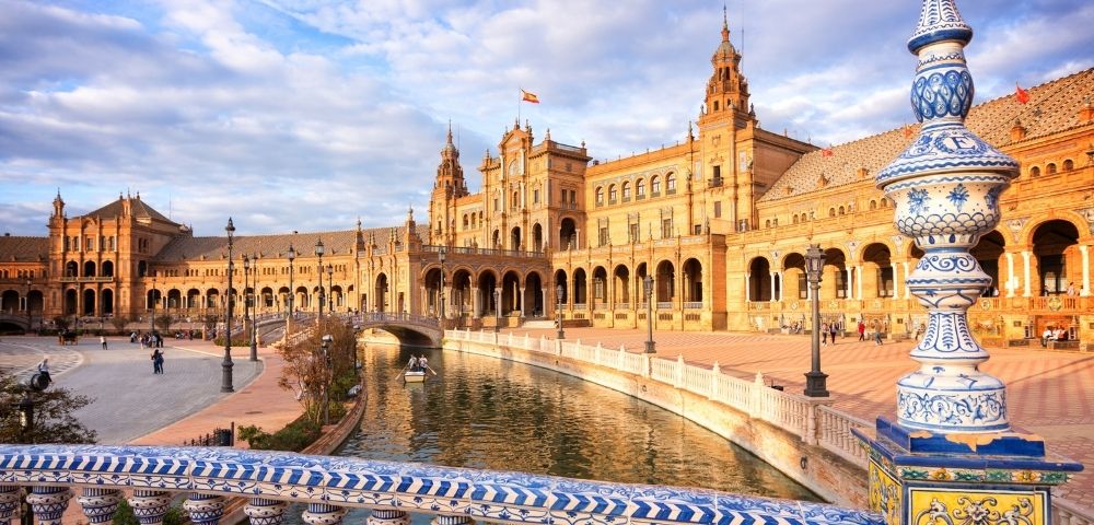 A view of a historic building with ornate architecture beside a canal, under a partly cloudy sky.