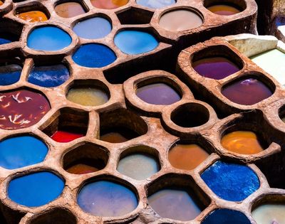 A close-up view of circular dye pits filled with vibrant colored liquids, arranged in a honeycomb pattern.