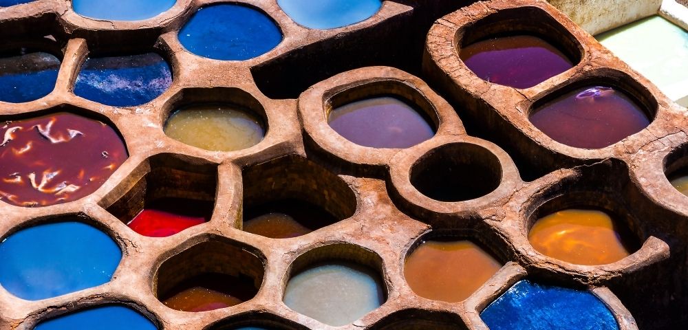 A close-up view of circular dye pits filled with vibrant colored liquids, arranged in a honeycomb pattern.