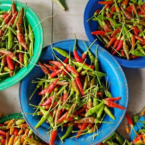 Overhead view of chili peppers piled in bowls, creating a vibrant, rustic market display.